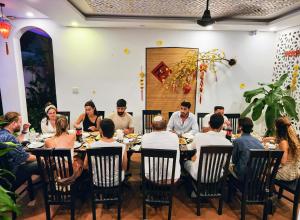 un grupo de personas sentadas alrededor de una mesa en un restaurante en Vincent's House, en Hoi An