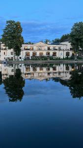 un riflesso di un edificio in un corpo idrico di Pałac na wodzie Falkowski Medical & SPA & Conference a Augustów