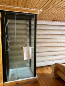 una ducha de cristal en una cabaña de madera con una toalla en Gostynna sadyba Kit Bayun en Teterivka