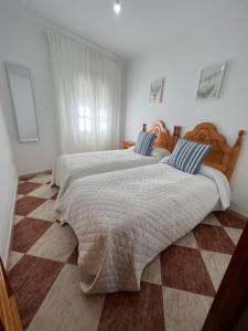 - une chambre avec 2 lits et un sol en damier dans l'établissement Casas PARAJE NATURAL, à Zahara de la Sierra