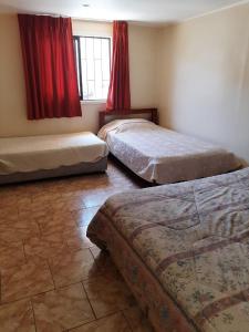 - 2 lits dans une chambre dotée de rideaux rouges dans l'établissement Linda casa con piscina en el quisco., à El Quisco