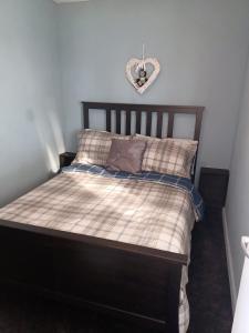 a bed with a heart sign on the wall at 2-bedroom Holiday Home With Great Outdoor Space in Kidwelly