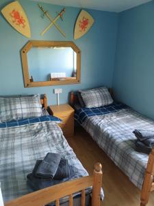 two beds in a room with a mirror at 2-bedroom Holiday Home With Great Outdoor Space in Kidwelly