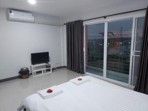 a bedroom with a white bed and a large window at Thana Apartment in Ban Phan Sadet Nai