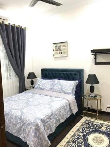 a bedroom with a blue bed with two lamps at SB PRIMA VILLA APRTMENT in Tanah Rata