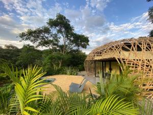 uma cabana de palha com duas cadeiras em frente em IslaVerde Hotel em La Mesa