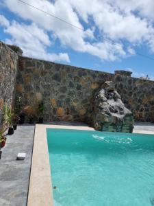 a swimming pool in front of a stone wall at Family Bungalow in Cap Malheureux