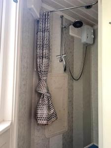 a shower stall with a shower curtain hanging from a door at The Shed . A cosy, peaceful, 96% recycled, chalet. in Swansea