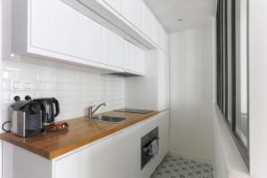 a white kitchen with a sink and a microwave at Eiffel Tower Royal Apartment in Paris