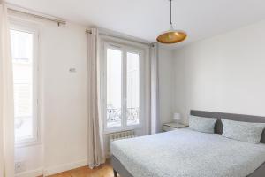 1 dormitorio blanco con 1 cama y 2 ventanas en Eiffel Tower Royal Apartment, en París