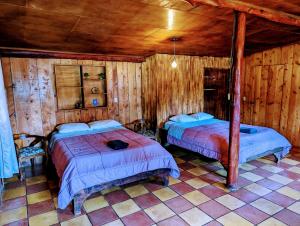 two beds in a room with wooden walls at Batsu EcoLodge & Coffee Farm in San Ramón
