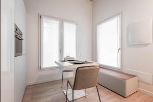 a white kitchen with a desk and two windows at Palazzo '900 Design Flats - L'Orologiaio in Padova