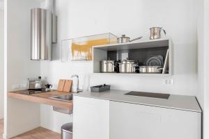 Palazzo '900 Design Flats - L'Orologiaio في بادوفا: مطبخ مع حوض وكاونتر مع القدور والمقالي