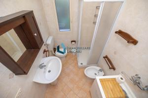 W łazience znajduje się umywalka, toaleta i umywalka. w obiekcie Villa Siragusa con piscina condominiale w mieście Campofelice di Roccella