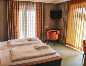 シュマレンベルクにあるParkhotel Schmallenbergのベッド2台とテレビが備わるホテルルームです。