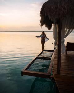 a woman walking on a dock in the water at Khaban Bacalar Hotel Boutique in Bacalar
