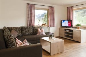 ein Wohnzimmer mit einem Sofa und einem TV in der Unterkunft Im Höfle Ferienwohnungen in Mittelberg