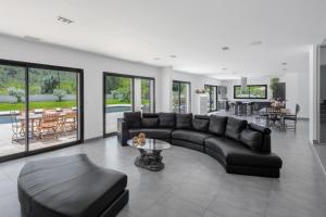 salon z czarną kanapą i stołem w obiekcie VILLA KOÏ CASTELLET*PISCINE*SPA*SALLE DE SPORT*CINÉMA* w mieście Cuges-les-Pins