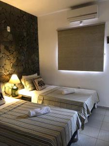 1 dormitorio con 2 camas y pared de piedra en Pousada Hosp Cantinho de Minas, en Cabo Frío