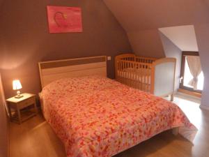 a small bedroom with a bed and a crib at La petite maison in Tauves