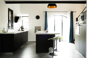 uma cozinha com armários pretos e um balcão branco em La Grange 1832 - A 10 mins d'Aubenas em Saint-Étienne-de-Boulogne