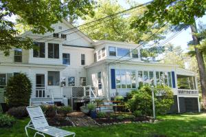 a white house with a chair in the yard at Sebago Suite in Standish