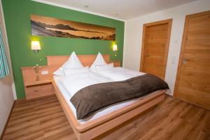 ein Schlafzimmer mit einem großen Bett und einer grünen Wand in der Unterkunft Im Höfle Ferienwohnungen in Mittelberg
