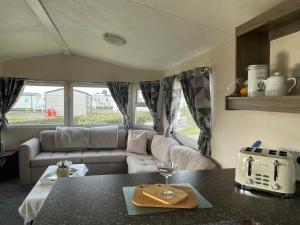 Trecco Bay Porthcawl Caravan 8 berth PALMS 4 في Newton: غرفة معيشة مع أريكة وطاولة