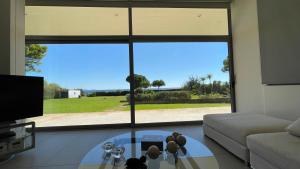 a living room with a glass table in front of a large window at Seaside Villa Hoopoe just steps from the beach in Schinias