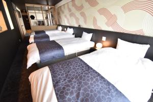 a hotel room with three beds and a wall at K-style gosyonishi in Shimmachidōri
