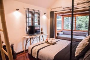 a bedroom with a bed and a tv and a couch at Ruanmata Homestay in Chiang Mai