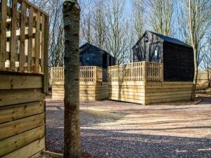 a wooden fence with two houses in the background at Fairwood Lakes Holiday Park- Fishing Breaks - Woodland Huts in North Bradley