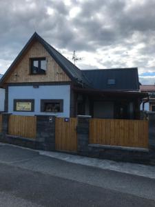 a house with a wooden fence and a building at Penzion Arrow in Lesná