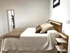 een slaapkamer met een groot bed met witte lakens en kussens bij Vivienda Turística Jaén Interior PARKING GRATUITO in Andújar
