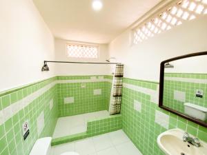 a green and white bathroom with a sink and a mirror at Mansion Bahia Manga in Cartagena de Indias