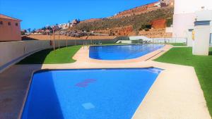 una piscina al lado de un edificio en Apartamento nuevo con piscina en la envía golf aguadulce Almería, en La Envía