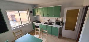 eine Küche mit grünen Schränken, einem Tisch und einem Fenster in der Unterkunft CASA_VISI in Gordoncillo