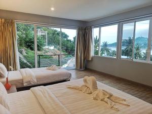 a bedroom with two beds and a large window at So Good Haad Rin Resort in Haad Rin