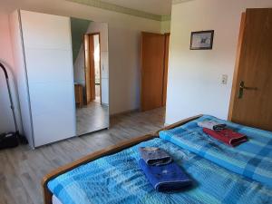 a bed with a blue comforter and a red suitcase and a mirror at Haus am Bürgerpark Hage OG in Hage
