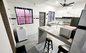 a white kitchen with a counter and stools in it at BK House Melaka in Malacca