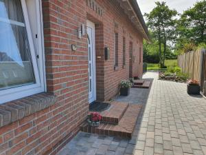 ein Backsteinhaus mit einer Tür und ein paar Blumen in der Unterkunft Haus am Bürgerpark Hage EG in Hage