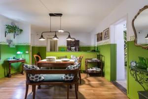 une salle à manger avec des murs verts, une table et des chaises dans l'établissement Le Giuggiole 5 posti letto in una casa ricca d'atmosfera, à Farra dʼlsonzo