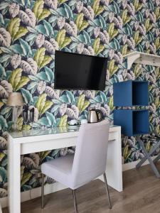 a desk with a tv on a wall with a tropical wallpaper at Corso Italia Rooms in Milan