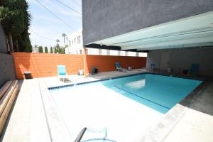 a swimming pool with two blue chairs next to a building at Hollywood Business Suites in Los Angeles