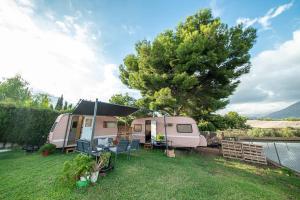 拉努西亞的住宿－Caravana- Glamping Casa tortuga，粉红色的大篷车,有帐篷和一棵树