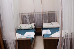 two twin beds in a room with curtains at Mujjo Hotel Kajjansi in Kampala