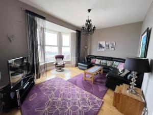 a living room with a black couch and a purple rug at The Beach Front Apartment, Amazing Frontline Sea Views in Tynemouth