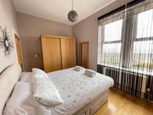 ein Schlafzimmer mit einem Bett und einem großen Fenster in der Unterkunft The Beach Front Apartment, Amazing Frontline Sea Views in Tynemouth