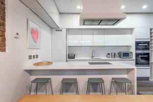 uma cozinha com armários brancos e um balcão com bancos em London Choice Apartments - South Kensington - Mews House em Londres
