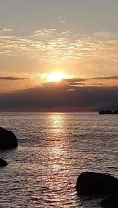 um pôr-do-sol sobre um corpo de água com pedras em Pousada Casa do Oscar em Governador Celso Ramos
